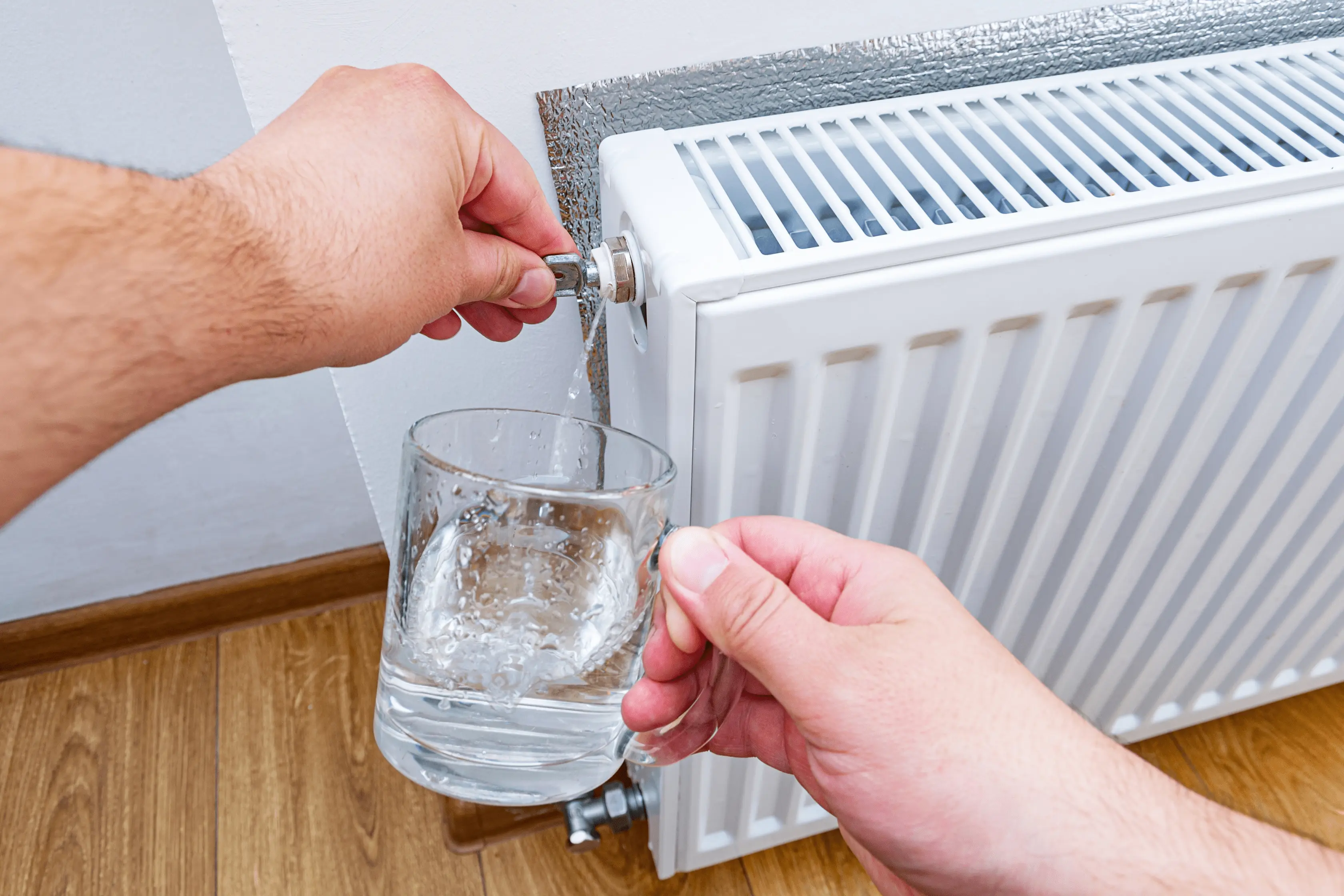 Homeowner Draining The Radiator With A Cup